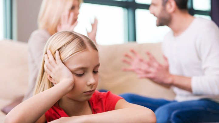 I hope they will work it out. Sad little girl leaning at the table and holding head in hand while her parents shouting at each other in the background